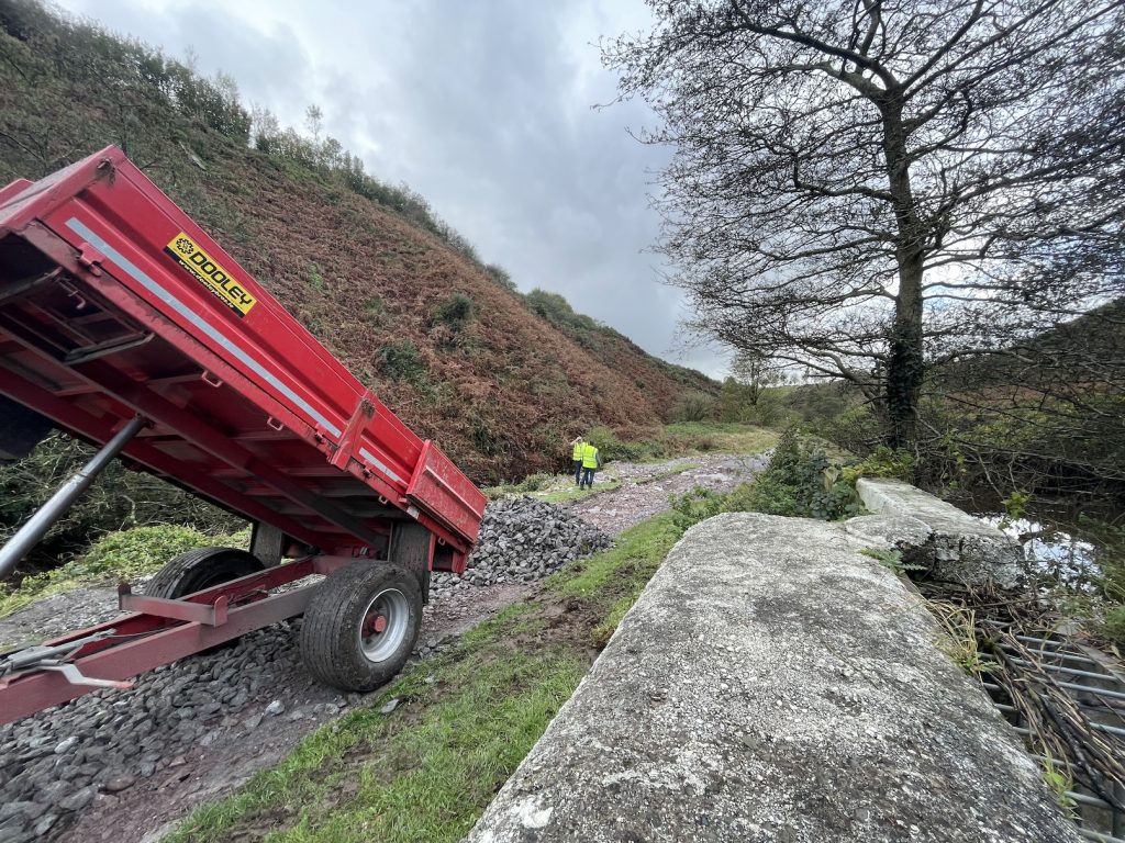 a photograph of a council truck emptying stones inot a hole