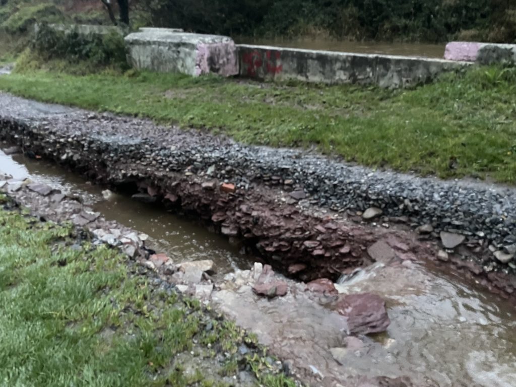 A photograph showing the gouge in the footpath caused by the fast flowing river