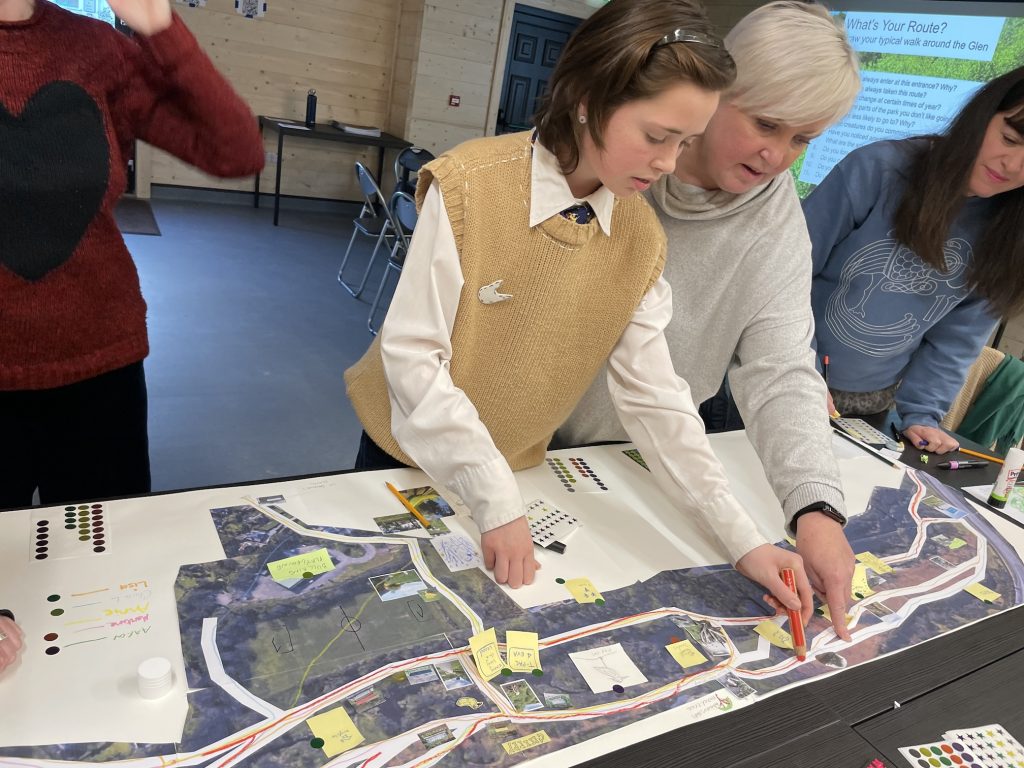 A photo of a mother and daughter drawing a route on a map