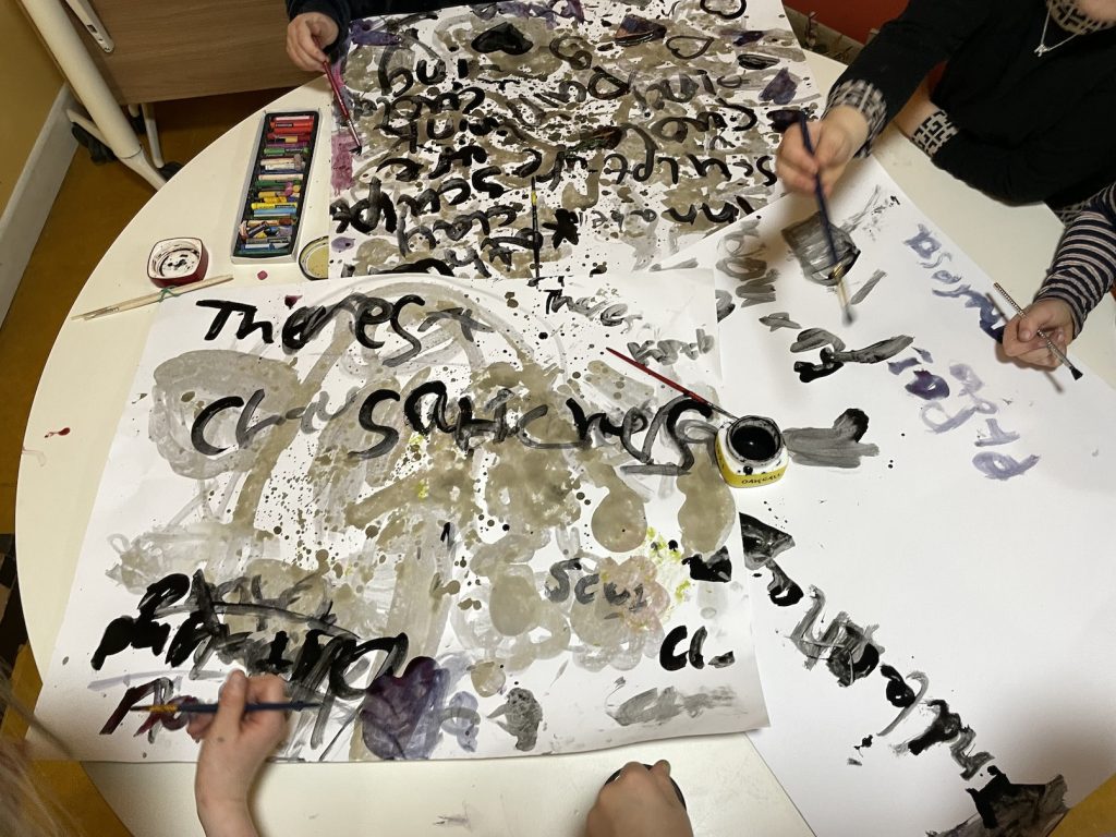 A round table with inky drawings and children's hands