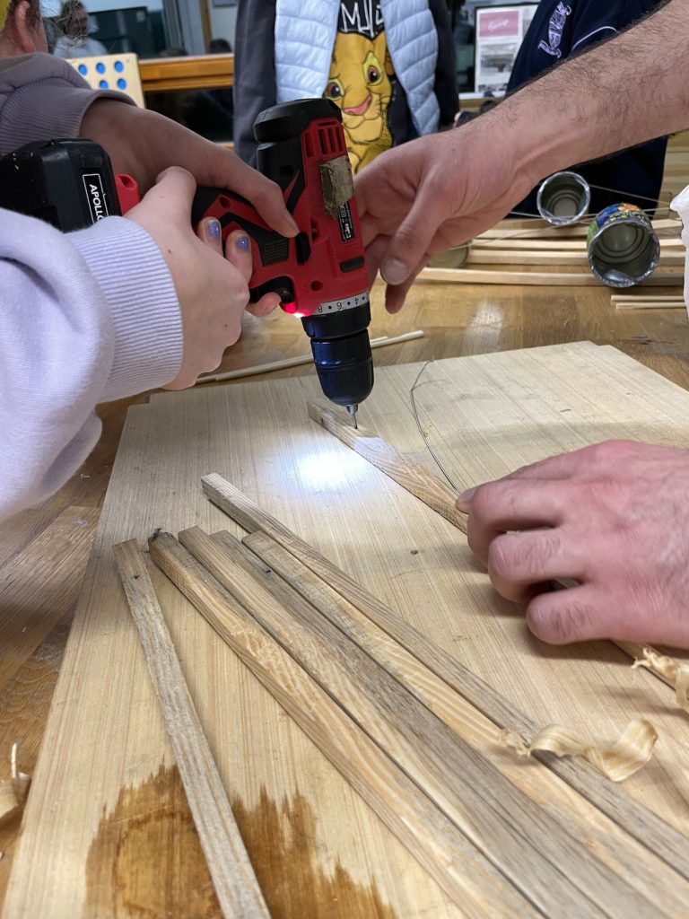 A photo of a child and an adults hands holding a drill