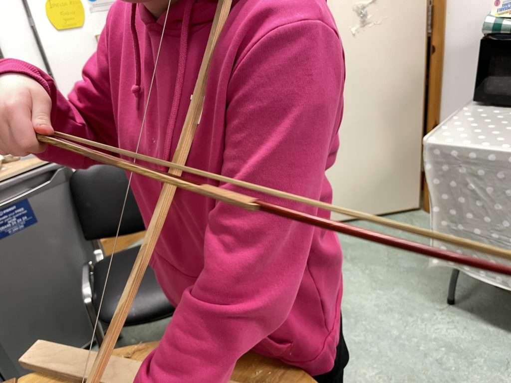 a child playing with her hand built instument