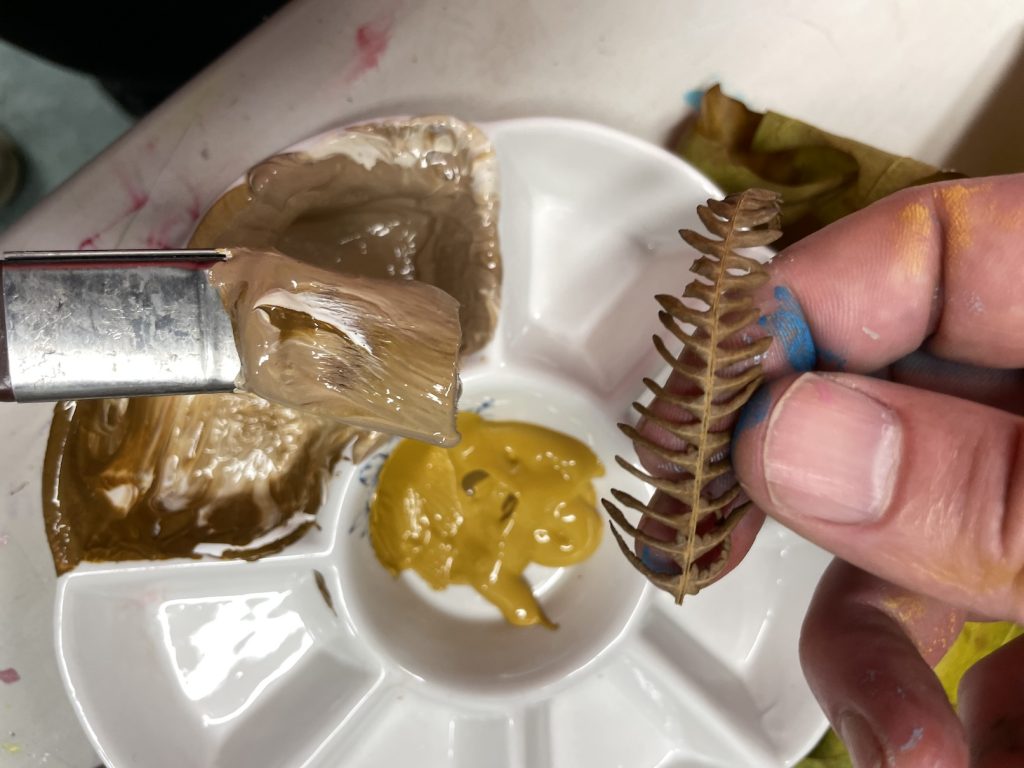 photo of a loaded paintbrush matching colours to a fern