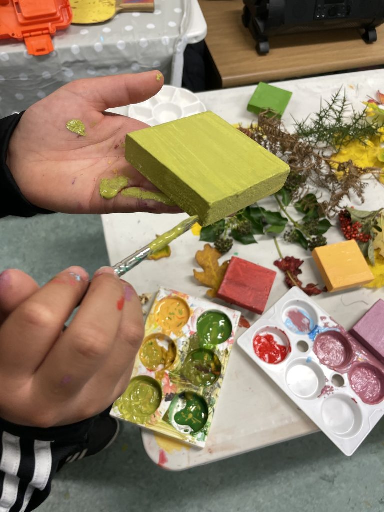 Photo of a pair of hands painting a wooden block green