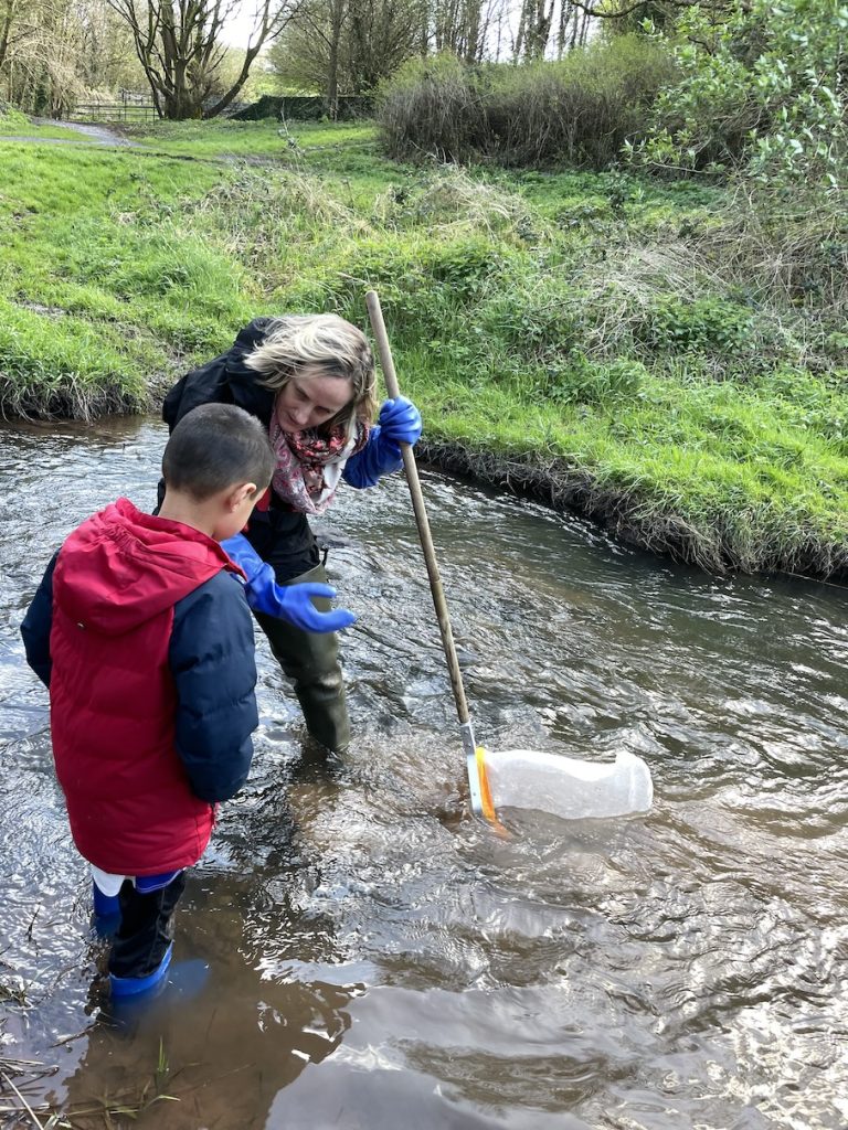 a woman and a child standing in the river with a net