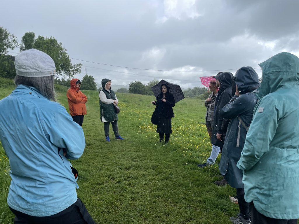 a photo of Dr. Jenny Butler on a hill under an umbrella with a small crowd of people