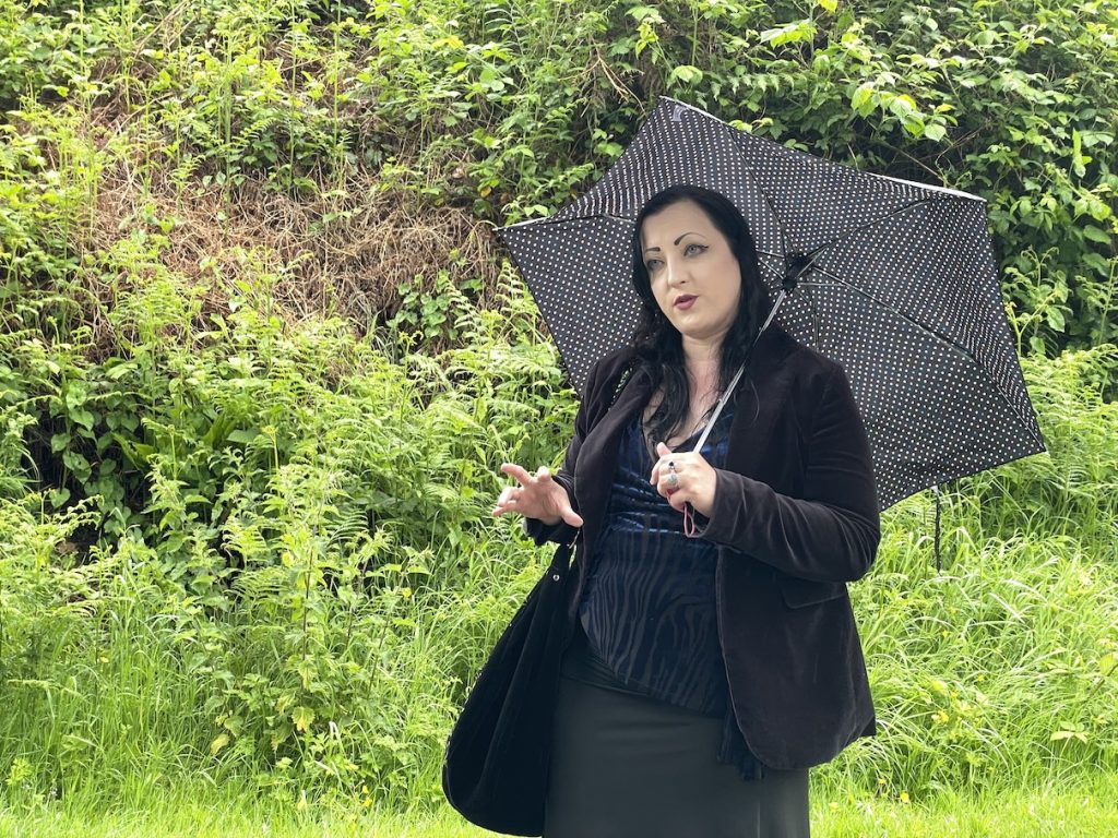 a photo of a woman wearing black under a spotted umbrella 