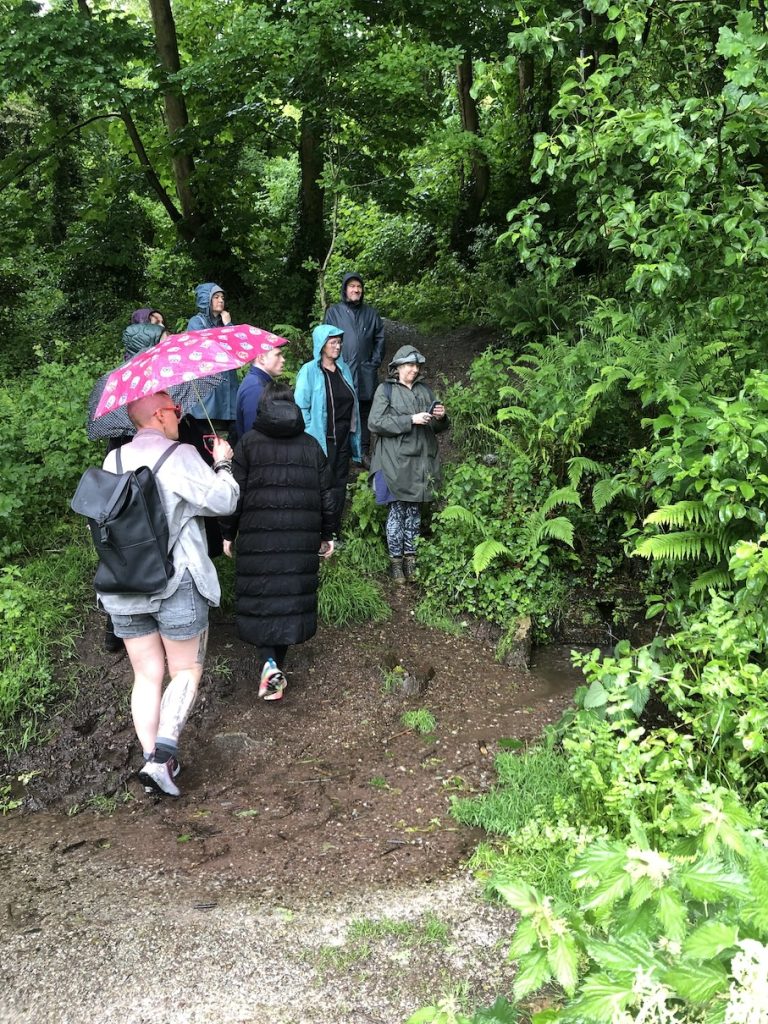 a photo of a small crowd under the trees by a well