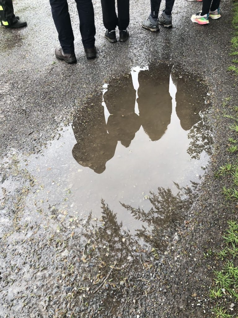 a photo of a reflection in a puddle and legs standing on the ground