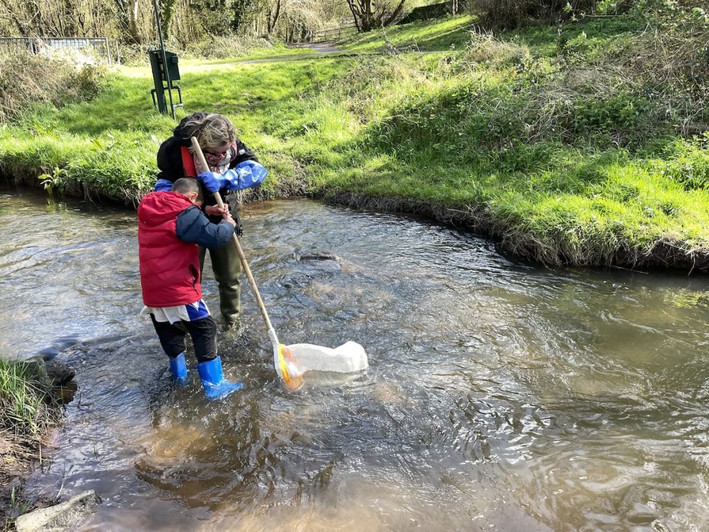 A woman and a boy standing in the river with a net