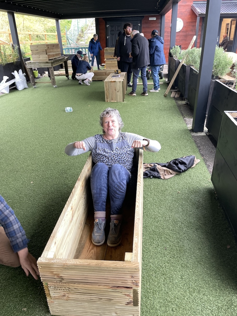 a woman sitting inside a wooden crate - she is pretending to row as if in a boat