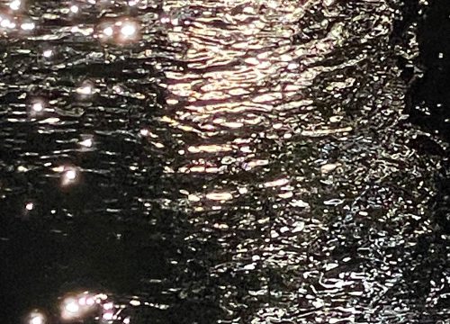 A photograph of dark water with ripples of light