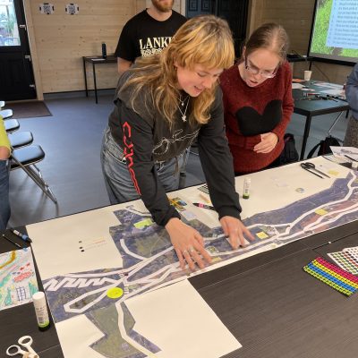 A woman is leaning over a map sticking down images