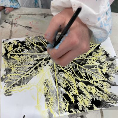 a photo of a child making a leaf drawing with ink and wax relief