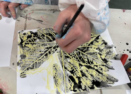 a photo of a child making a leaf drawing with ink and wax relief