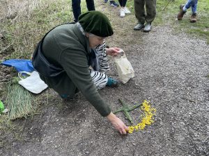 A photo of elinor rivers beginnng to create the mandala - laying gorse flowers around a Brigid's cross