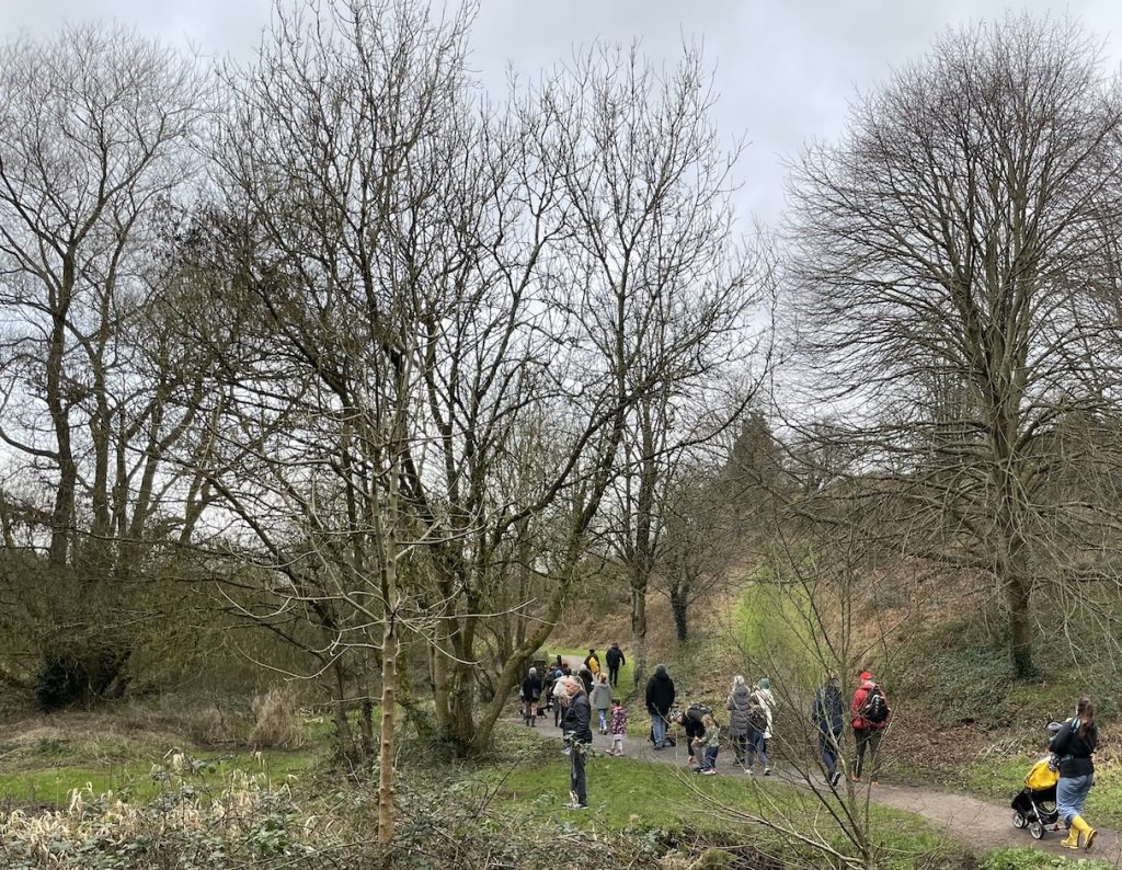 a photo of people walking and listening aiong the Glen river's bank