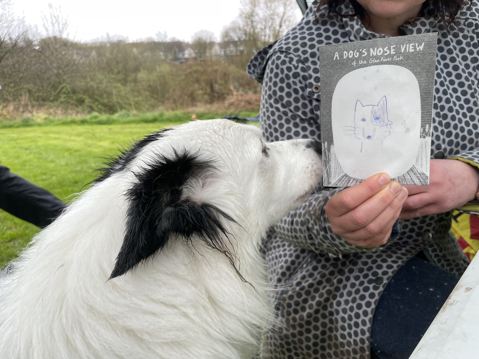 A photo of a dog and a human with a zine in her hand