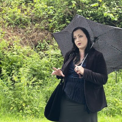 a photo of a woman wearing black under a spotted umbrella