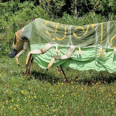 A costume of a monster worn by several people in a park in summer