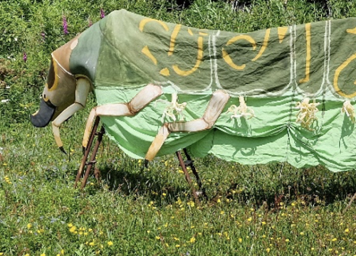 A costume of a monster worn by several people in a park in summer