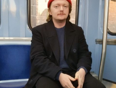 an image of a man wearing a red hat and sitting on a train